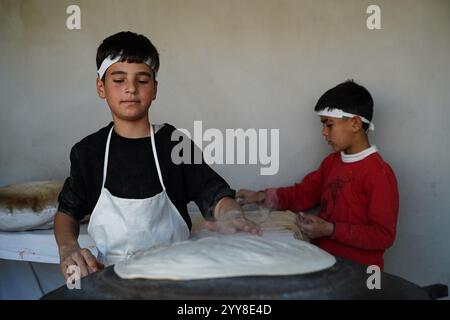 Kinder arbeiten in einer Bäckerei im Lager Domiz für syrische kurdische Flüchtlinge etwa 18 km südwestlich von Duhok in der Region Kurdistan. Die Provinz Duhok beherbergt 92.000 syrische Flüchtlinge von 275.000 Flüchtlingen in der Region Kurdistan im Irak, die seit Ausbruch der syrischen Revolution im Jahr 2011 migriert sind. Die meisten von ihnen weigern sich, trotz des Sturzes des Baschar al-Assad-Regimes in ihr Land zurückzukehren, aus Angst vor dem Ausbruch bewaffneter Konflikte zwischen den syrischen Demokratischen Kräften (SDF) und der von der Türkei unterstützten syrischen Nationalarmee oder mit Hayat Tahrir al-Sham und anderen Oppositionskräften, die kooperiert haben Stockfoto