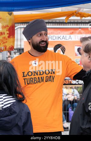 Fröhlicher Freiwilliger mit der Chardikala Turban Academy beim Vaisakhi Festival am Trafalgar Square, der Veranstaltung, die traditionelle Sikh-Kultur feiert. Stockfoto
