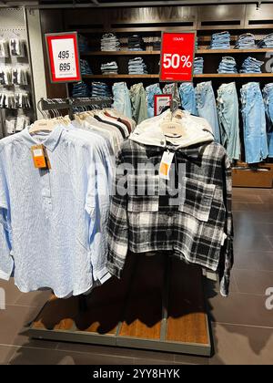 Kiew, Ukraine - 18. Dezember 2024: Gezeigt wird ein Kleiderständer im Laden, in dem karierte Jacken und lässige Jeans zu einem ermäßigten Angebot präsentiert werden, betont Stockfoto