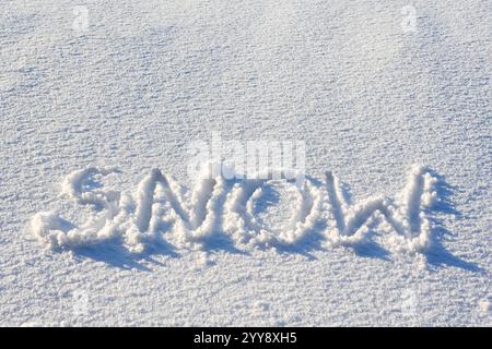 Das Wort Schnee steht auf Neuschnee an frostigen sonnigen Tagen. Kann wie bei Weihnachtsfeiertagen verwendet werden Stockfoto