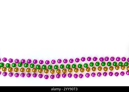 Mardi Gras Perlen in traditionellen lila, goldenen und grünen Farben isoliert auf weißem Hintergrund mit Kopierraum Stockfoto