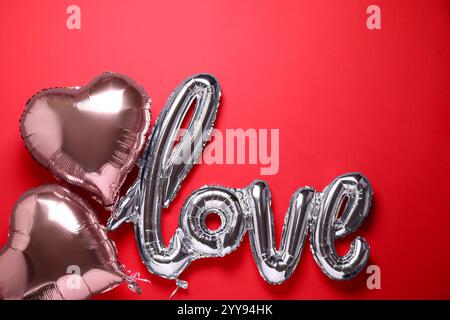 LIEBESWORTE und Herzballons auf rotem Hintergrund, flach liegend Stockfoto