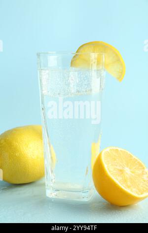 Soda-Wasser mit Eiswürfeln im Glas und frischen Zitronen auf hellblauem Hintergrund Stockfoto