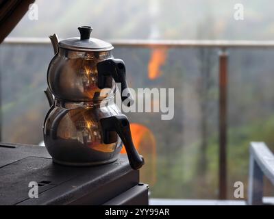 Ein traditioneller doppelter Teekessel aus Edelstahl oder türkischem Caydanlik wird auf einem Kaminofen beheizt Stockfoto