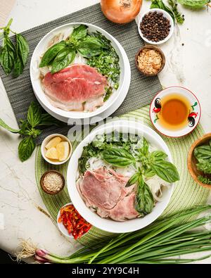 Eine Schüssel authentischer vietnamesischer Pho mit seltenem Rindfleisch, frischem Basilikum, Zwiebeln und aromatischen Kräutern, bereit zum Servieren mit reichhaltigem, aromatischem brot Stockfoto