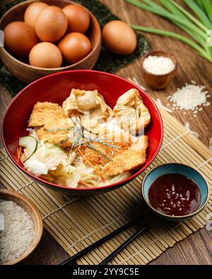 Blick von oben auf eine lebendige asiatische Mahlzeit mit mehreren roten Schüsseln gefüllt mit verschiedenen Reis- und Nudelgerichten, einschließlich gegrilltem Fleisch, Gemüse, Stockfoto