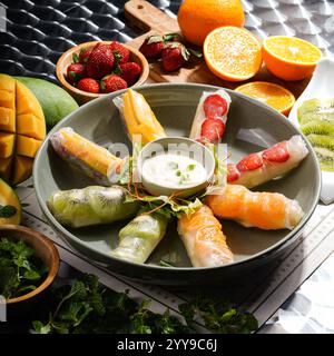 "🍓🥭 tropische Frische bei jedem Bissen! Diese Frühlingsbrötchen sind vollgepackt mit saftiger Mango, Kiwi, Erdbeere und Orange, verpackt in Feinkost Stockfoto