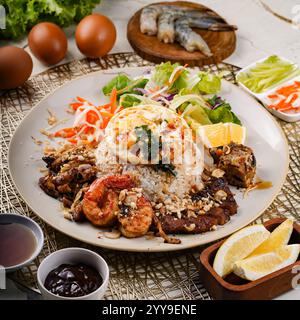 Ein wunderschön überzogenes vietnamesisches Cơm Tấm (gebrochener Reis) Gericht mit gegrilltem Schweinefleisch, Garnelen, Spiegelei, frischem Salat und garniert mit Erdnüssen. Stockfoto