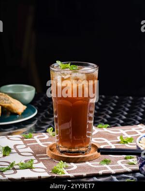 Ein erfrischendes Glas vietnamesischer Eistee garniert mit Pfefferminze – knusprig, kühl und der perfekte Begleiter für eine herzhafte Mahlzeit. Stockfoto