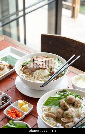 Eine warme und angenehme Schüssel vietnamesischer Pho mit zarten Rindfleischscheiben, frischen Kräutern und seidigen Reisnudeln in einer duftenden Brühe, serviert mit cl Stockfoto