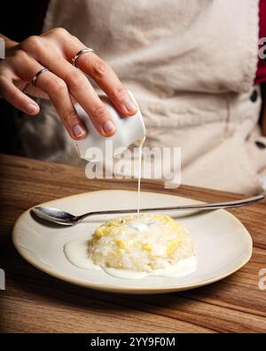 Eine Nahaufnahme von thailändischem Mango-Kleberreis, der mit reichhaltiger Kokosnusscreme getränkt wird. Dieses beliebte südostasiatische Dessert kombiniert süßen klebrigen Reis, frisch Stockfoto