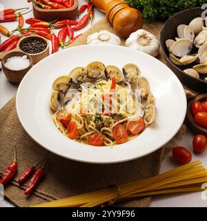 Klassische Spaghetti Bolognese in einer weißen Schüssel serviert, umgeben von frischen Zutaten wie Zwiebeln, Knoblauch, Tomaten und Petersilie. Ein herzhaftes italienisches Gericht Stockfoto