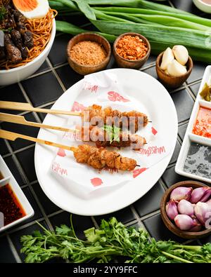 Eine köstliche Portion gegrillter Schweinesieße, perfekt verkohlt und mit kräftigen asiatischen Gewürzen und Beilagen serviert, umgeben von frischen Kräutern Stockfoto