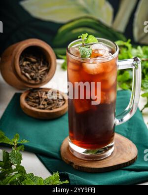 Drei erfrischende Eistee in hohen Gläsern mit Eiswürfeln, frischen Minzblättern und verschiedenen Fruchtstücken, wunderschön auf einem weißen Glas angeordnet Stockfoto
