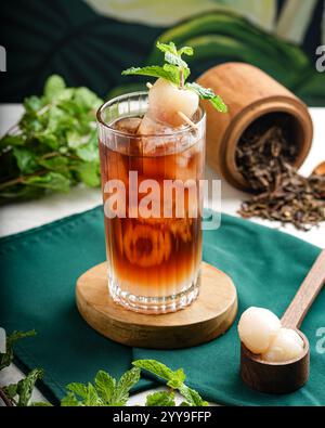 Drei erfrischende Eistee in hohen Gläsern mit Eiswürfeln, frischen Minzblättern und verschiedenen Fruchtstücken, wunderschön auf einem weißen Glas angeordnet Stockfoto