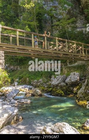 Mutter und Kind genießen den atemberaubenden Blick auf das türkisfarbene Wasser der tolmin-Schlucht von einer malerischen Brücke, umgeben von üppigem Grün Stockfoto