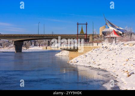 Eine Brücke über einen Fluss mit einem roten Zelt auf der rechten Seite. Die Brücke ist mit Schnee bedeckt und das Wasser ist gefroren Stockfoto