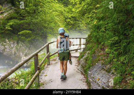 Die Mutter trägt ihr Kind bei einer Wanderung an einem nebeligen Sommertag in der vintgar-Schlucht in der Nähe von Bled, slowenien, und genießt einen malerischen Spaziergang durch die Natur Stockfoto