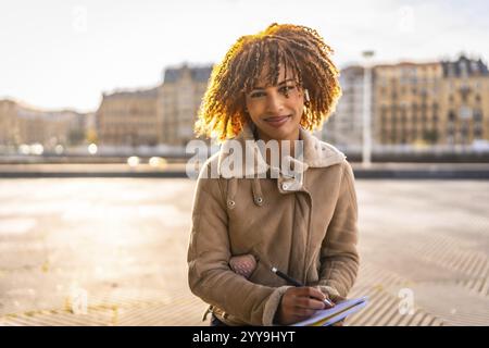 Schöne lateinische Frau, die in der Stadt auf Notizbuch skizziert Stockfoto