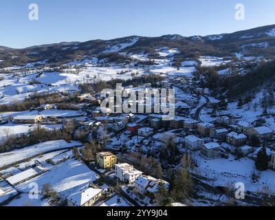 Blick aus der Vogelperspektive auf Morfasso, ein kleines Dorf in der Emilia Romagna, Norditalien, das während der Wintersaison von Schnee bedeckt ist, mit schneebedeckten Dächern, Straßen A Stockfoto