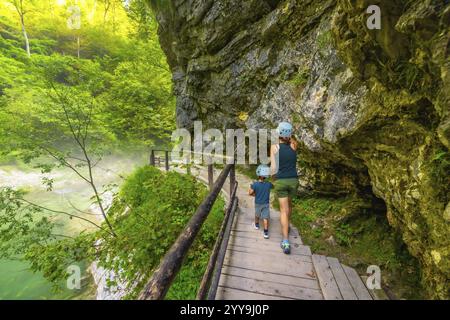 Touristen, die Helme tragen, genießen eine Wanderung durch die malerische vintgar-Schlucht in der Nähe von Bled, slowenien, die auf einer hölzernen Fußgängerbrücke über einen klaren Fluss spaziert Stockfoto