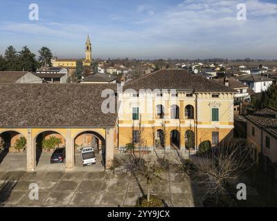 Aus der Vogelperspektive von Stagno Lombardo, Italien, zeigt Wohnhäuser, bewirtschaftetes Ackerland und die Infrastruktur der Stadt unter einem klaren blauen Himmel, Europa Stockfoto