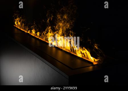 Dramatische Nahaufnahme eines modernen linearen Ethanol-Kamins mit hellen gelben Flammen, die eine luxuriöse Atmosphäre für zeitgenössische Innenarchitektur schaffen Stockfoto