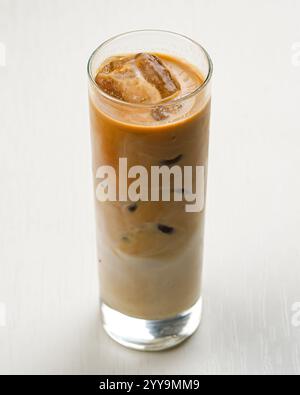 Hohes Glas Eiskaffee mit Milch, gefüllt mit Eiswürfeln und serviert auf einem weißen Tisch Stockfoto
