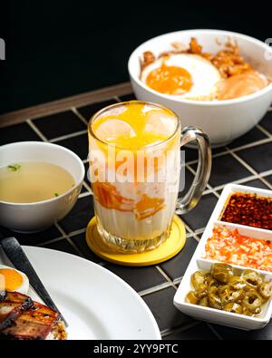 Erfrischender tropischer Mango-Smoothie mit Schlagsahne, Mangobacken und frischem Minzzweig – gekühlt in einem hohen Glas serviert Stockfoto