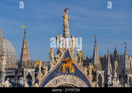 Venedig, Italien - Markusdom oben auf der Westfassade mit Markusstatuen, flankiert von Engeln und geflügeltem Markuslöwen. Stockfoto