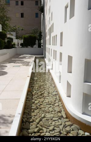 Rechteckiges Wasserspiel mit glatten Steinen, das ein minimalistisches und beruhigendes Design in einem modernen urbanen Ambiente widerspiegelt Stockfoto