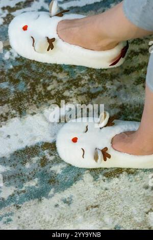Frau mit lustigen, wildrohförmigen, weichen weihnachtsschuhen. Bewegt sie spielerisch vor den weihnachtsbaum. Stockfoto