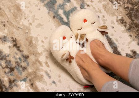 Frau mit lustigen, wildrohförmigen, weichen weihnachtsschuhen. Bewegt sie spielerisch vor den weihnachtsbaum. Stockfoto