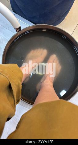 Pediküre Fuß Bad Konzept, Schönheit asiatische junge Frau tränkt Hygienefüße in Schüssel zu Hause, Fuß im Wasser für weiche Füße Haut im Schönheitssalon Spa Pedicus Stockfoto