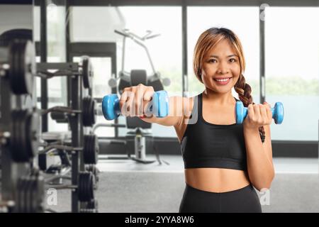 Asiatische Frau, die mit Kurzhanteln in einem Fitnessstudio trainiert Stockfoto