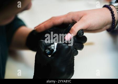 Schönheitsnägel-Konstruktion. Untere Nagelverlängerungen. Meister-Maniküre im Schönheitssalon erhöht die Nägel durch Verlängerung der Nagelplatte des Kunden mit Acryl oder Stockfoto