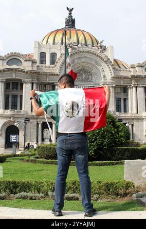 Mexiko-Stadt, Mexiko - 6. September 2023: Der Mann hält die mexikanische Flagge vor dem Palacio de Bellas Artes, um die nationalen Feiertage der Unabhängigkeit zu feiern Stockfoto