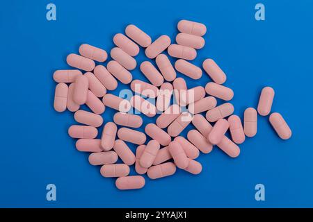 Nahaufnahme eines Stapels rosafarbener Pillen auf blauer Oberfläche, Gesundheitskonzept. Stockfoto