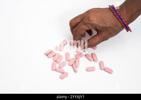 Draufsicht einer weiblichen Hand, die eine rosafarbene Pille auf einem klaren weißen Hintergrund nimmt. Gesundheitskonzept Stockfoto