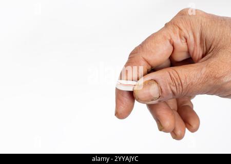 Ein Nahbild einer Hand, die eine beschädigte Pille vor einem weißen Hintergrund hält. Gesundheitskonzept Stockfoto