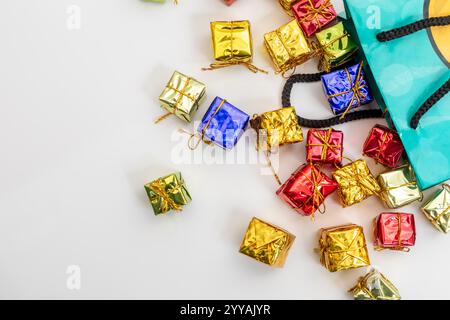 Farbenfrohe Miniatur-Geschenkboxen aus einer festlichen grünen Tasche. Perfekt für Geschenke, Feiertage und glückliche Anlässe. Stockfoto
