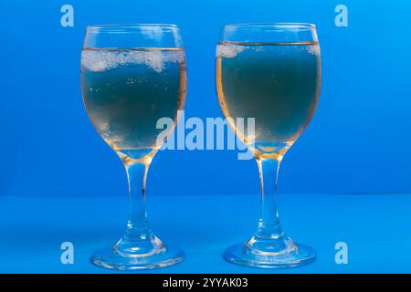 Zwei Gläser Weißwein mit Eis auf einem leuchtend blauen Hintergrund. Nahaufnahme Stockfoto