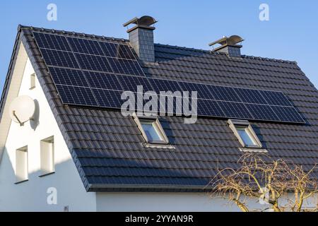 Sonnensystem auf dem Dach eines Einfamilienhauses mit zwei Schornsteinen Stockfoto