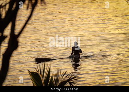 Mann schwimmt auf einem Baumstamm in Ruanda Stockfoto