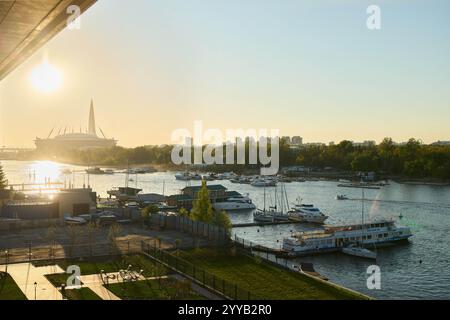 Ein ruhiger und ruhiger Blick auf den Sonnenuntergang auf einen sich windenden Fluss mit sanft schwimmenden Booten und einer atemberaubenden Skyline der Stadt Stockfoto