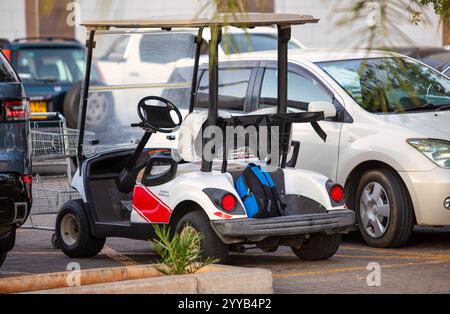 Parkplatz Supermarkt, Golfwagen-Sicherheitsdienst parkt und wartet zwischen den Autos, moderne afrikanische Mall Entwicklung Stockfoto