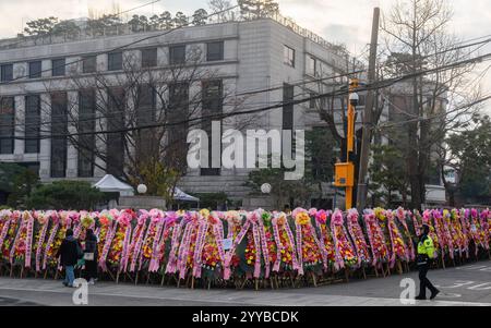 Seoul, Südkorea. Dezember 2024. Ein Polizist steht mit Kränzen, die von Anhängern des angeklagten südkoreanischen Präsidenten Yoon Suk Yeol vor dem Verfassungsgericht in Seoul geschickt wurden. Das südkoreanische Verfassungsgericht wägt seine Optionen ab, da eine Reihe von Dokumenten, mit denen das Amtsenthebungsverfahren gegen Präsident Yoon Suk Yeol eingeleitet wurde, ihm nach fünf Tagen nicht zugestellt wird, sagte ein Gerichtssprecher am 20. Dezember. Quelle: SOPA Images Limited/Alamy Live News Stockfoto