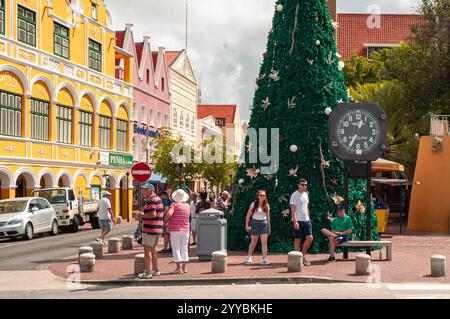 Willemstad, Curacao, Niederlande - 6. Januar 2018: Touristen, die einen sonnigen Tag in der Nähe eines großen Weihnachtsbaums im farbenfrohen Stadtzentrum genießen. Stockfoto