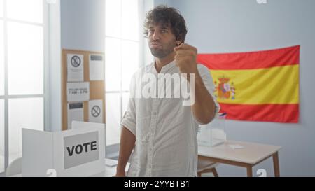 Junger Mann in weißem Hemd in einem Wahlraum mit spanischer Flagge, der seine Stimme abgibt, einen Hauch von Entschlossenheit und Konzentration ausstrahlt und Bürgersinn symbolisiert Stockfoto