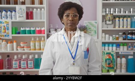 afroamerikanische Frau mit lockigem Haar, Brille und weißem Mantel, die in einer Apotheke steht, umgeben von Regalen voller verschiedener Produkte, Förderbänder Stockfoto